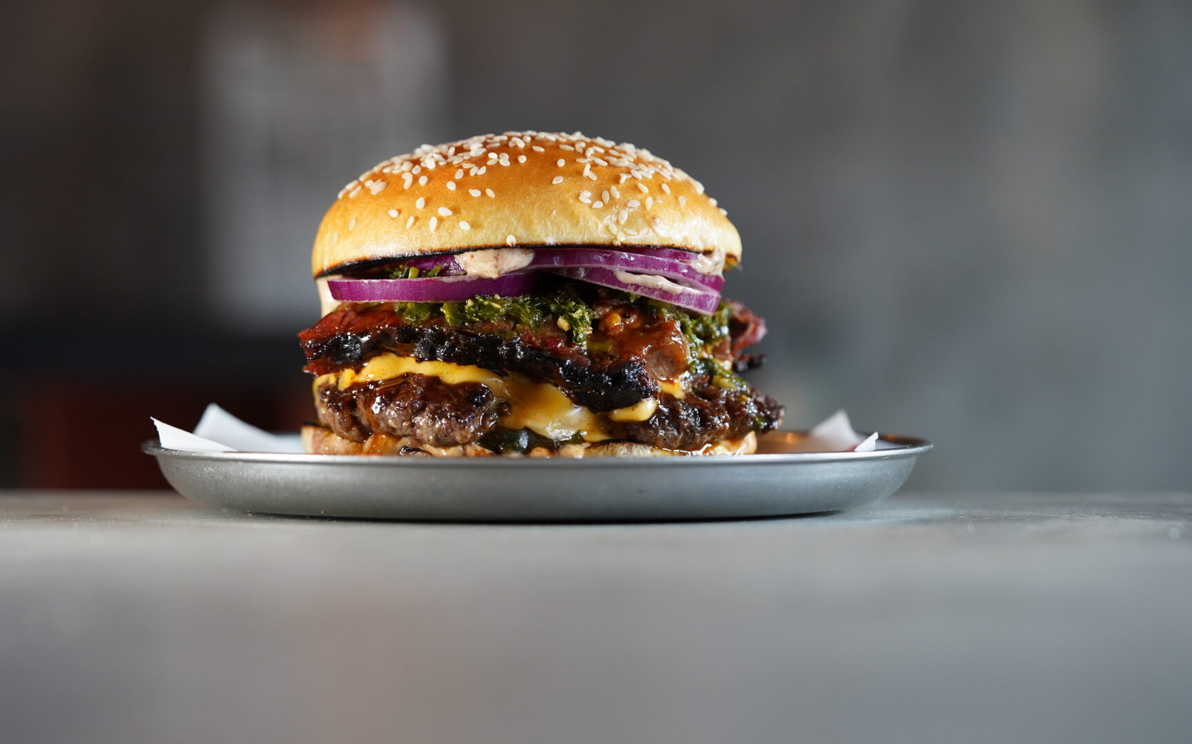 A large burger, filled with tomato, onion, lettuce and cheese.