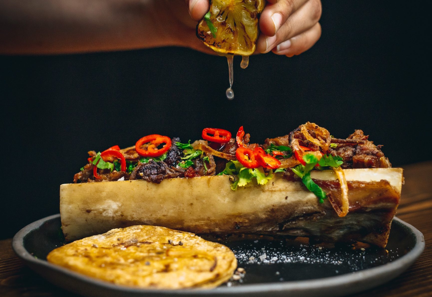 Squeezing a charred lemon across a dish
