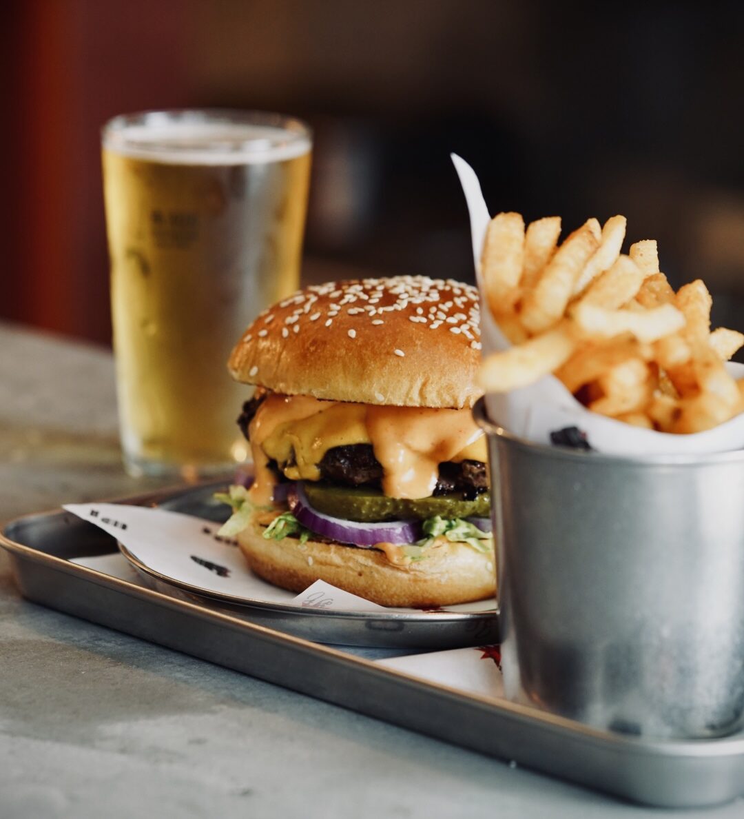 A pint of beer, burger and side of fries.
