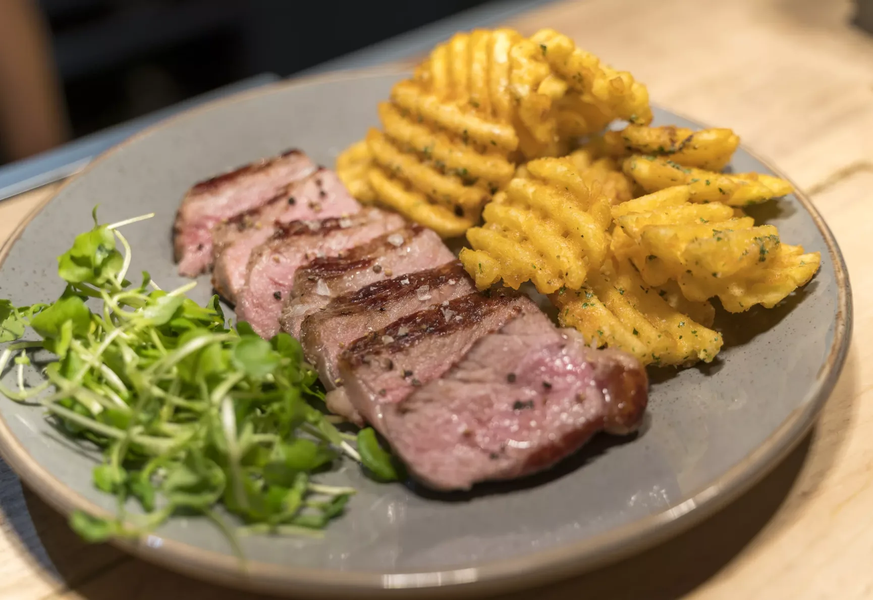 Succulent Steak on the side of fries and greens.